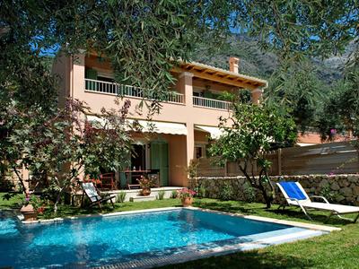 Two-story house with terrace, garden, and clear swimming pool under trees.