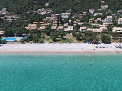 A white sandy beach with clear turquoise water and a coastline lined with hotels and greenery.
