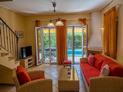 Bright living room with red upholstered furniture, tiled floor, and pool view.