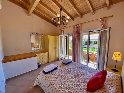 Cozy bedroom with wooden beam ceiling, double bed, balcony, and wood flooring.