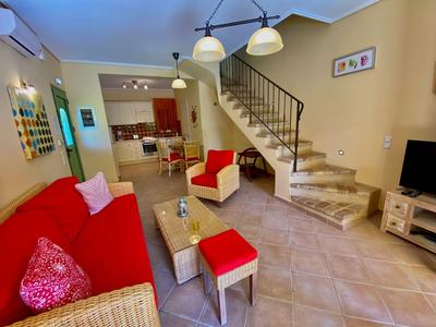 Cozy living area with red furniture, open kitchen, and staircase in a holiday home.