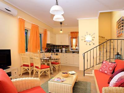 Bright living room with red sofas, dining area, and staircase in a cozy vacation apartment.