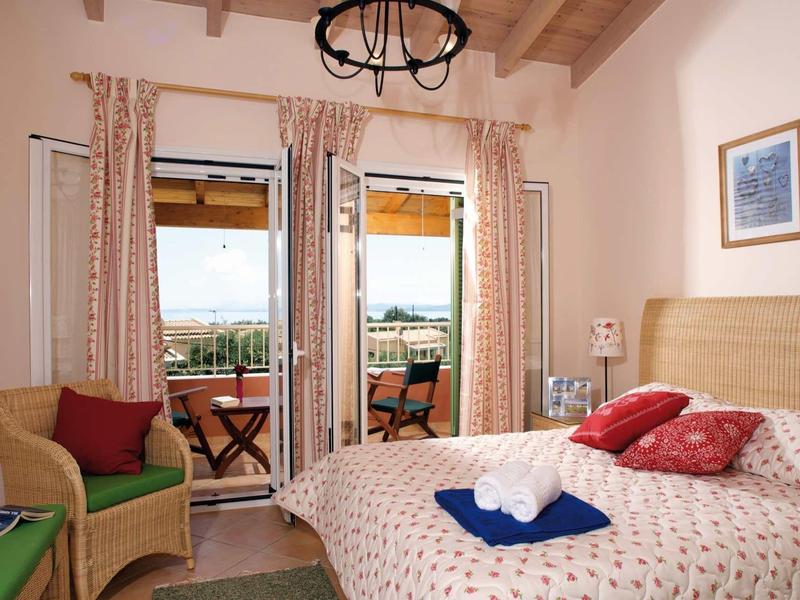 Gemütliches Schlafzimmer mit Holzdecke, Doppelbett, Sessel, Balkon und Blick ins Grüne.