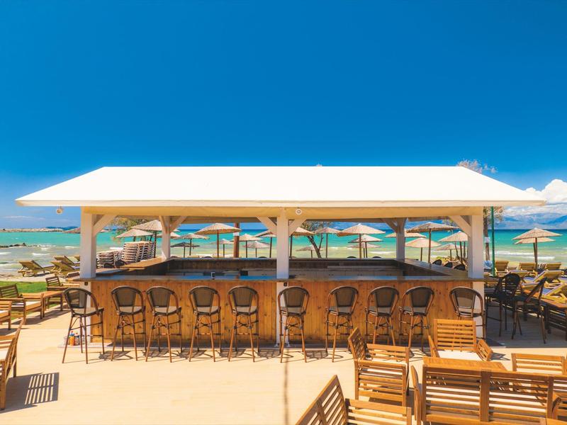 Bar am Strand mit Blick auf das türkisfarbene Meer und Sonnenschirme.