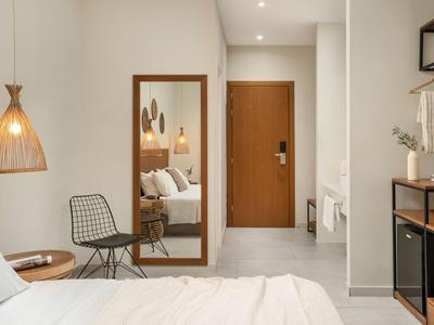 Modernes Schlafzimmer mit weißem Bett, Holzdetails, Stuhl aus Metall und beleuchtetem Spiegel.