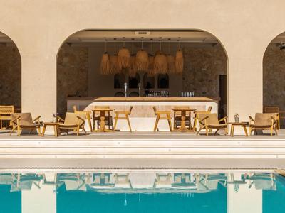 Area esterna moderna con bar, posti a sedere e piscina con acqua azzurra e limpida.