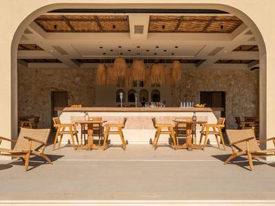 Area esterna moderna con sedie in legno e bar sotto un tetto in pietra.