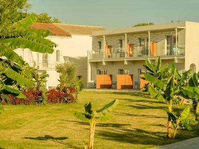 Edificio moderno dell'hotel con balconi e giardino con prato e piante tropicali
