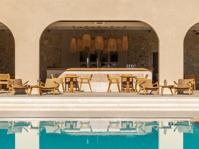 Moderner Außenbereich mit Holzstühlen, Bar und blauem Schwimmbecken im Vordergrund.