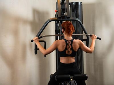 Femme aux cheveux rouges s'entraîne sur un appareil de musculation dans une salle de sport.