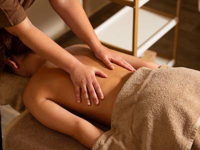 Person erhält Rückenmassage auf einem Massagetisch in entspannter Umgebung.