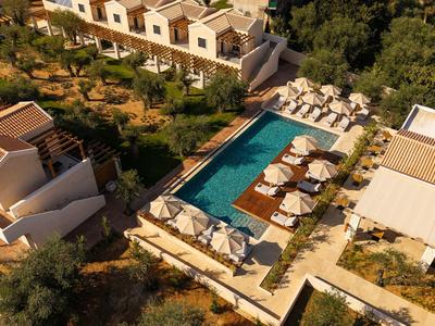 Vogelperspektive eines Resorts mit Pool, Sonnenliegen und Gartenanlagen bei Sonnenuntergang.