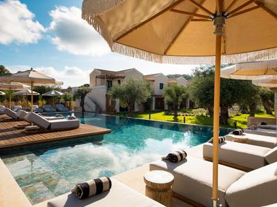 Espace piscine luxueux d'hôtel avec transats et parasols sous un ciel clair.