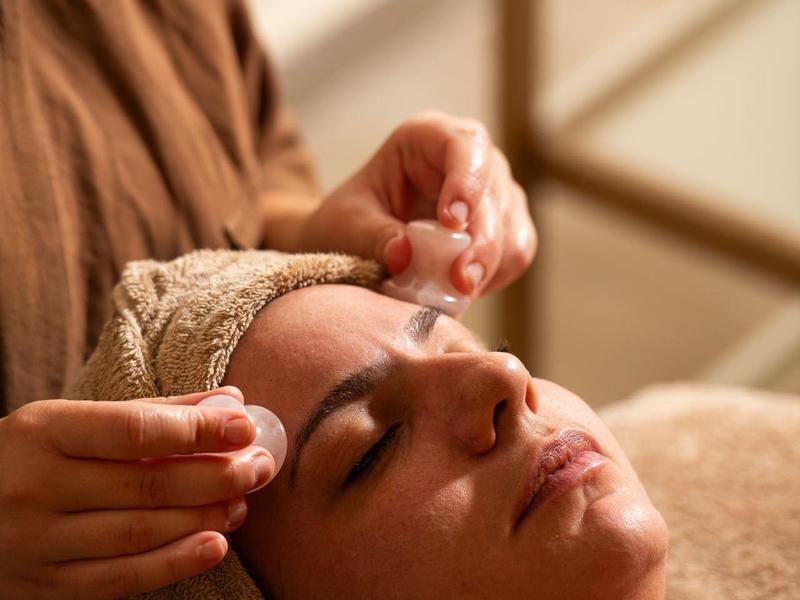 Person entspannt sich bei einer Gesichtsbehandlung in einem Wellnessbereich.