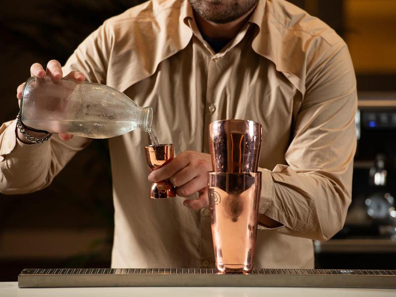 Barkeeper gießt ein Getränk in ein Messglas an einer Hotelbar.