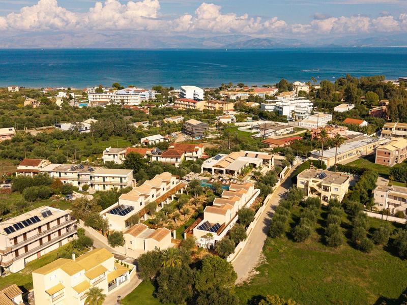 Panoramablick auf ein Küstenhotelresort mit weißen Gebäuden, Straßen und umgeben von viel Grün.