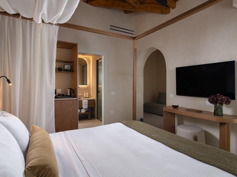 Gemütliches Hotelzimmer mit Doppelbett, Fernseher und schlichter Holzmöblierung.