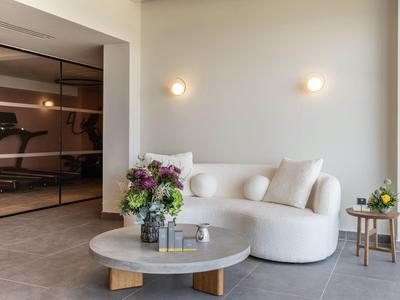 Moderner Wohnbereich mit weißem Rundsofa, grauem runden Tisch und Blumenarrangements.