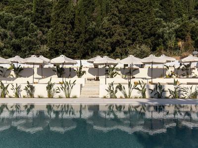 Rząd białych parasoli i leżaków obok basenu z drzewami w tle.