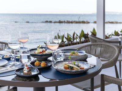 Elegancka restauracja z widokiem na morze, stół nakryty wykwintnym jedzeniem i winem.