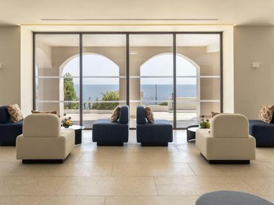 Nowoczesny salon z wygodnymi fotelami i widokiem na morze przez duże okna.