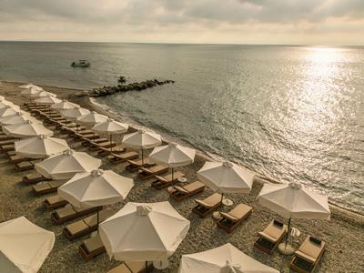 Rzędy leżaków z białymi parasolami na plaży o zachodzie słońca.