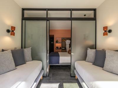 Modernes Wohnzimmer mit zwei weißen Sofas, grauen Kissen und Glasschiebetür zum angrenzenden Raum.