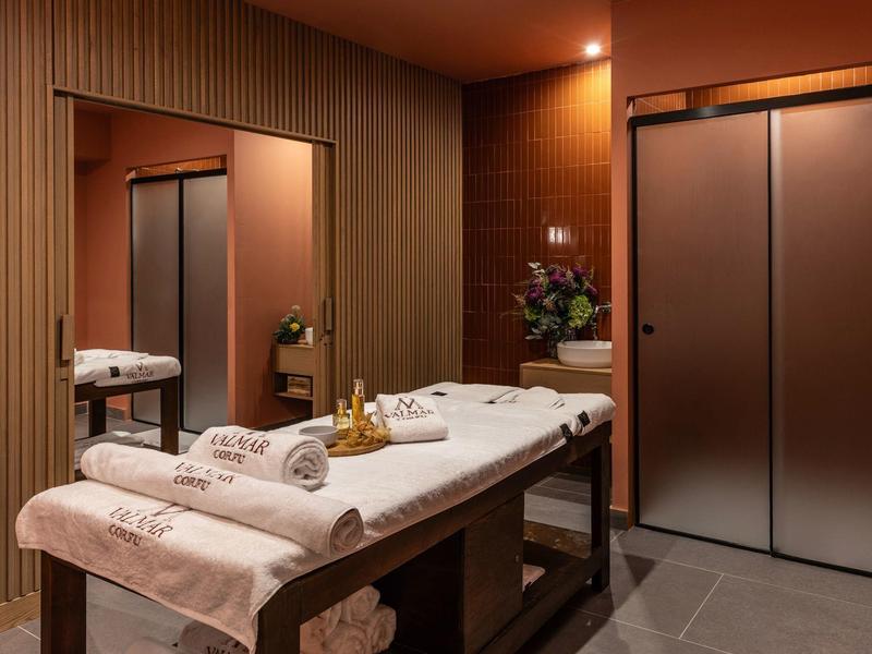 Eleganter Behandlungsraum mit Massageliege, warmen Holzvertäfelungen und sanfter Beleuchtung.