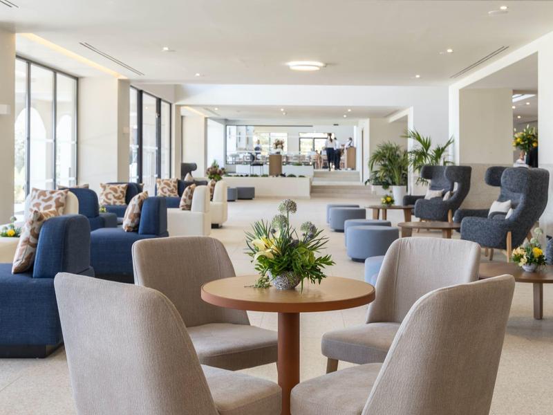 Helles, modernes Café mit runden Tischen, bequemen Sesseln und großen Fenstern für viel Tageslicht.