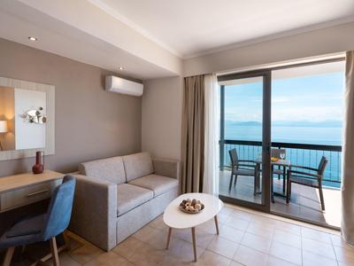 Moderner Raum mit grauer Couch, blauem Stuhl, kleinem Tisch und Balkon mit Meerblick.