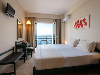 Modernes Hotelzimmer mit Doppelbett, Schreibtisch, Balkon und Meerblick bei Tageslicht.