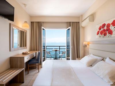 Habitación de hotel luminosa con cama doble y balcón con vistas al mar.