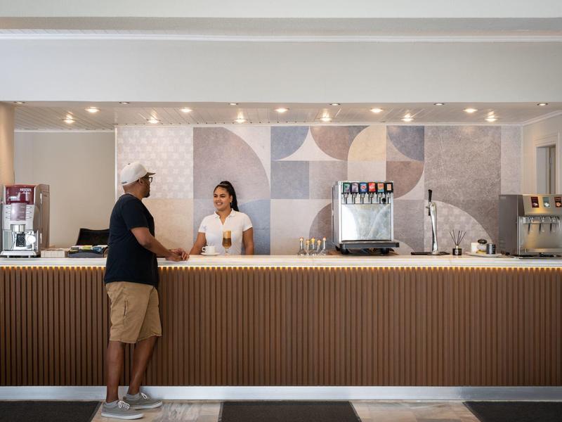 Moderne Café-Theke mit Holzfront, Kaffeegeräten und zwei Personen im Gespräch.