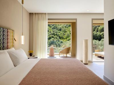 Gemütliches Hotelzimmer mit großem Bett und Blick auf einen bewaldeten Hügel.