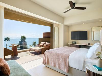 Camera d'hotel moderna con balcone, vista mare e comodo letto matrimoniale.