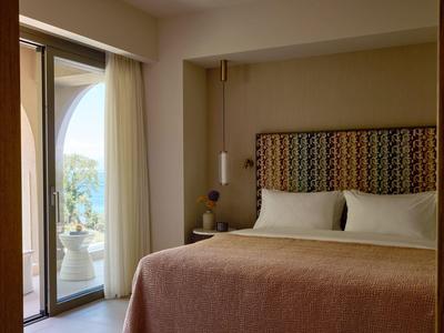 Gemütliches Schlafzimmer mit Doppelbett, gemustertem Kopfteil und Blick auf einen Balkon mit Meerblick.