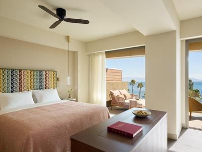 Modernes Hotelzimmer mit Balkon, Meerblick und gemütlicher Einrichtung bei Tag.