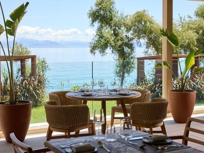 Tisch mit zwei Stühlen auf Terrasse mit Blick auf Meer und Bäume