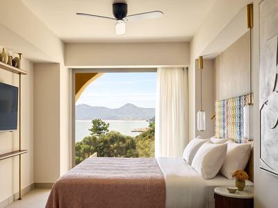 Modernes Hotelzimmer mit großem Bett und Meerblick durch eine offene Balkontür