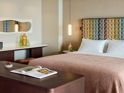 Gemütliches Hotelzimmer mit großem Bett, dekorativem Kopfteil und modernem Design.