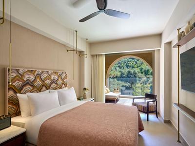 Helles Hotelzimmer mit großem Fenster, Doppelbett und Schreibtisch mit Blick auf die Natur.