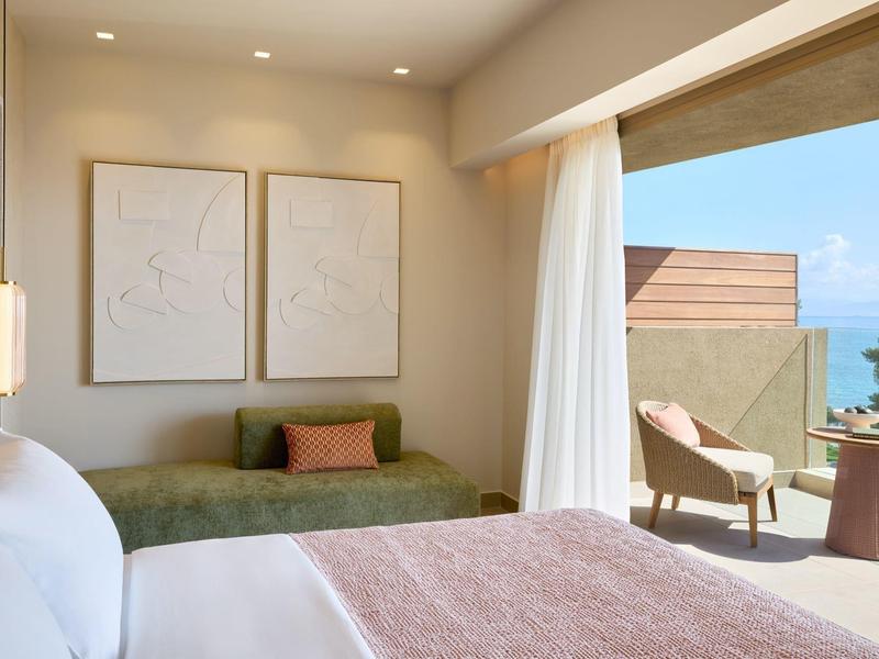Modernes Hotelzimmer mit gemütlichem Bett und Sitzbereich mit Blick auf Balkon und Meer.