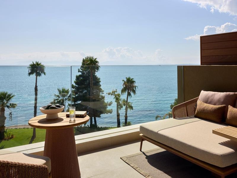 Terrasse mit Loungemöbeln und Meerblick sowie Palmen am Ufer
