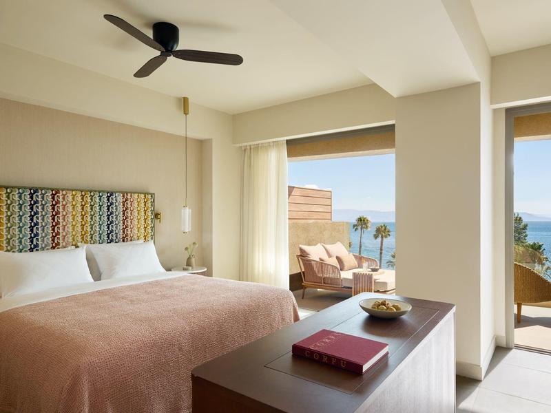 Modernes Hotelzimmer mit Balkon, Meerblick und gemütlicher Einrichtung bei Tag.