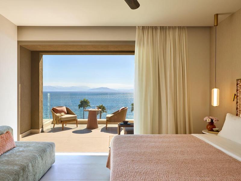 Modernes Hotelzimmer mit Meerblick, Terrasse und Gartenmöbeln.