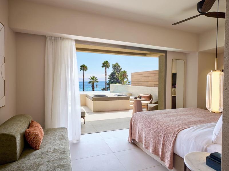 Modernes Schlafzimmer mit Balkon, Meeresblick und bequemen Sitzgelegenheiten.