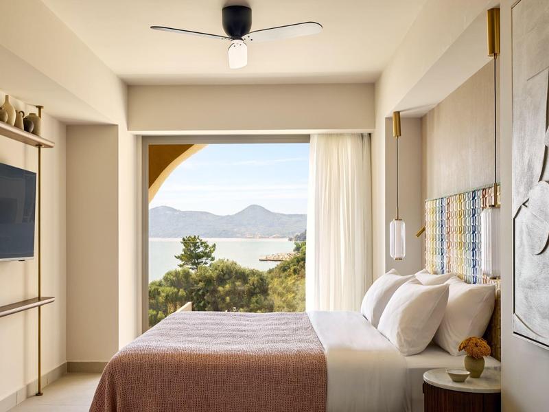 Modernes Hotelzimmer mit großem Bett und Meerblick durch eine offene Balkontür