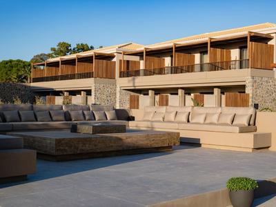 Moderner Außenbereich mit beigen Sofas, Steintisch und zweistöckigem Gebäude im Hintergrund.