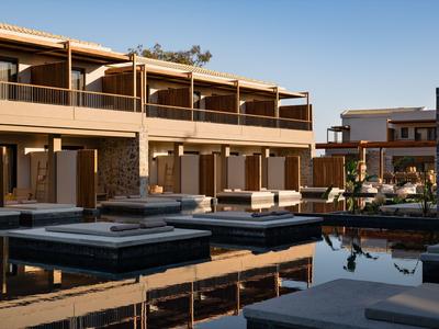 Moderner Hotelkomplex mit Außensitzbereichen und Wasserbecken unter klarem Himmel.