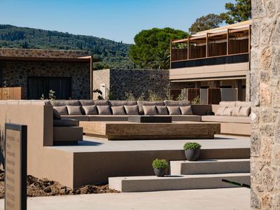 Moderner Außenbereich mit Sitzbänken und Blick auf bewaldete Hügel im Hintergrund.